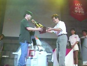 Yu Suzuki awarding the winner of a Virtua Fighter 3 tournament.